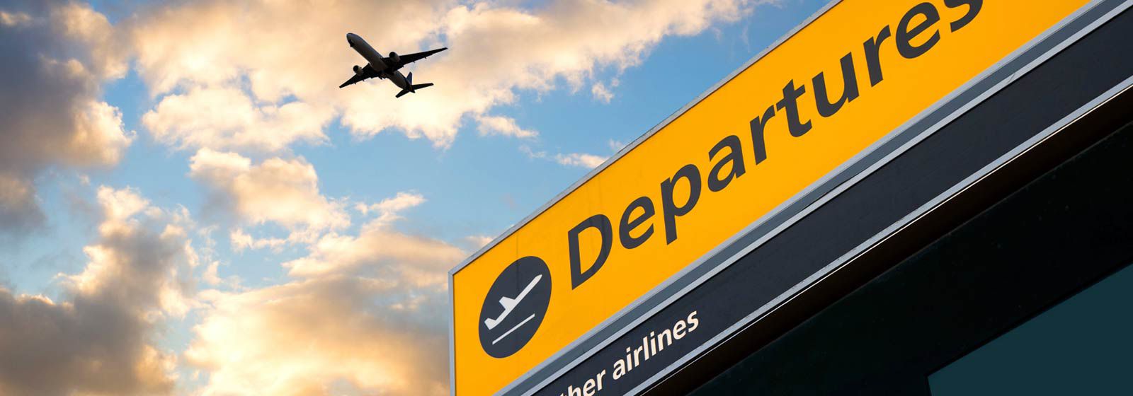 Yellow departure sign with airplane flying above it 