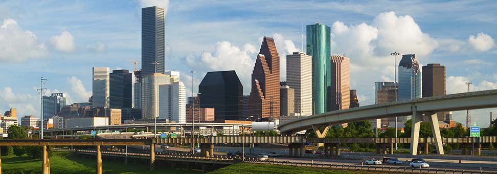 Skyline of Houston. Freeways with skyscrapers behind. Blues skies with clouds