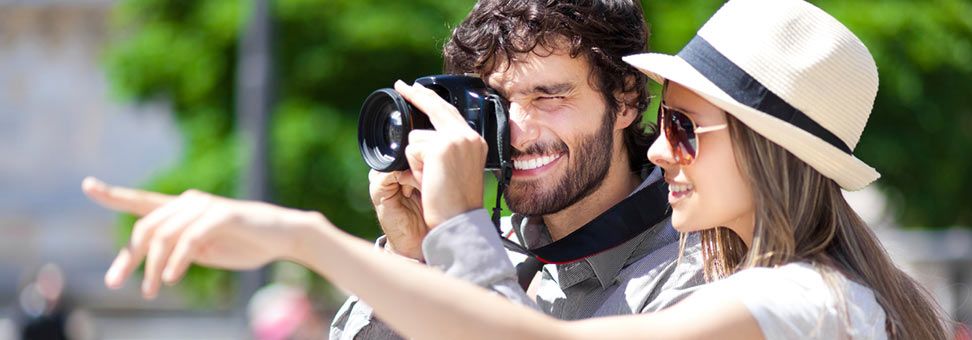 Couple standing together, woman pointing and man taking a photograph