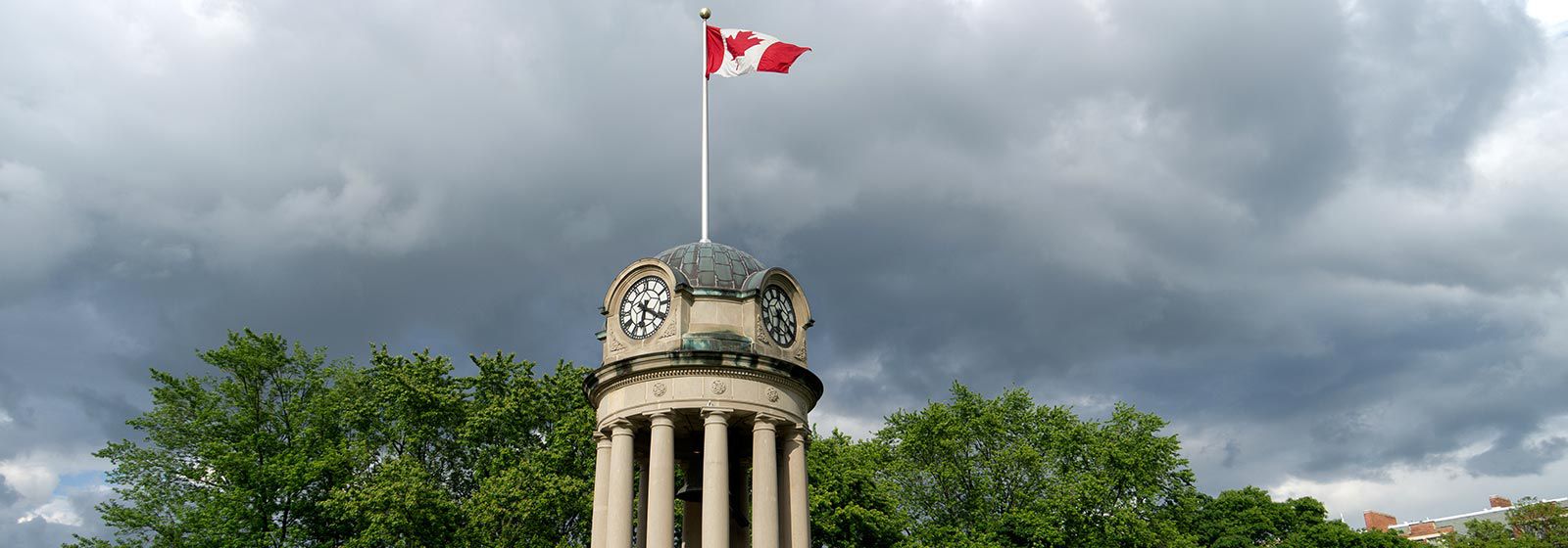 Clock tower, with flag of Canada raised above it, in London, Canada