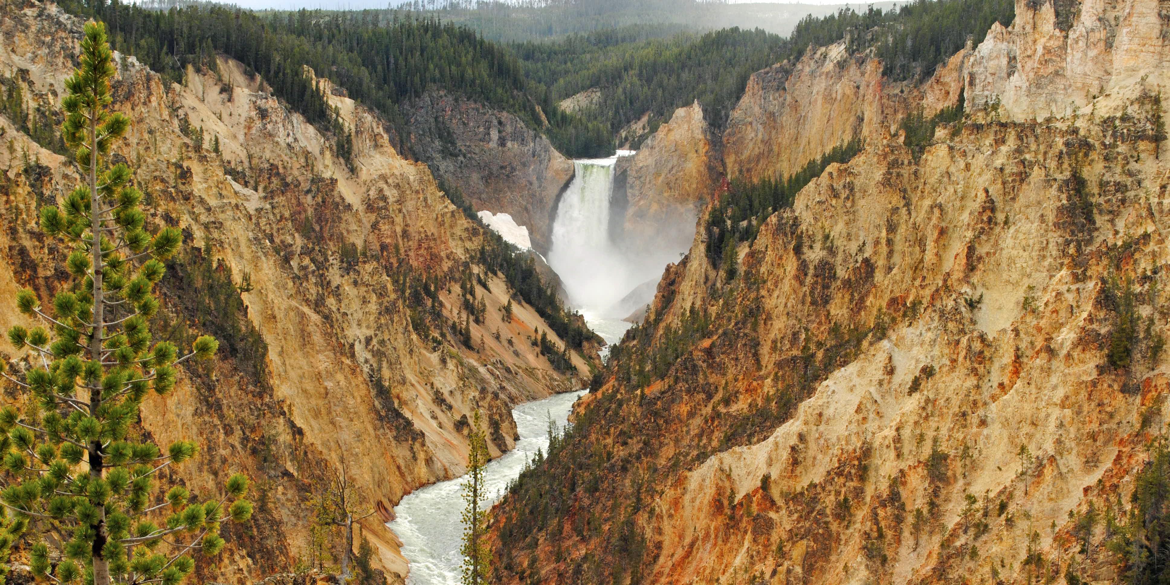 Waterfall and river in between two tan rocky mountains