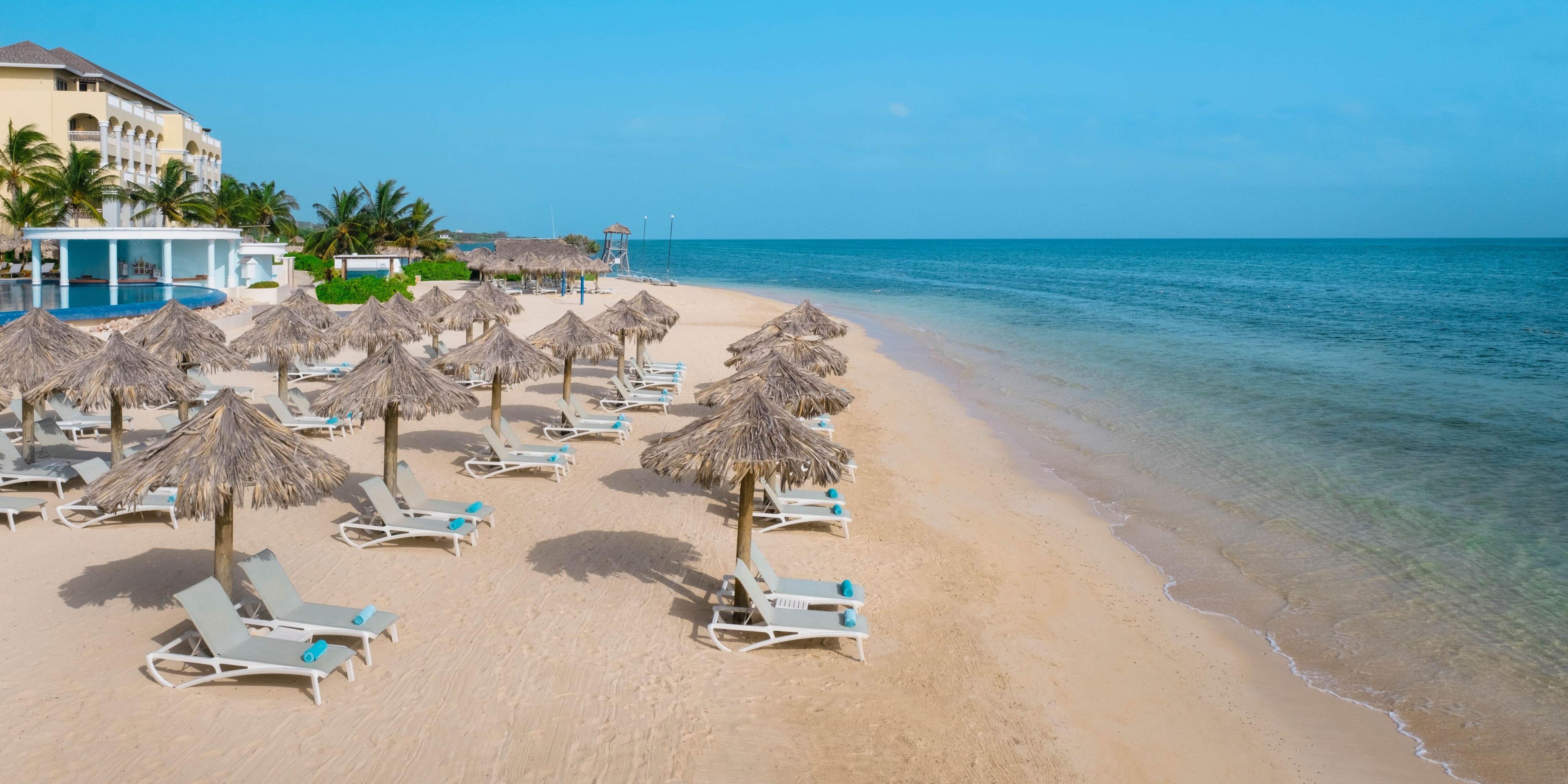 View of lounge chairs and thatch umbrellas on the beach in Montego Bay