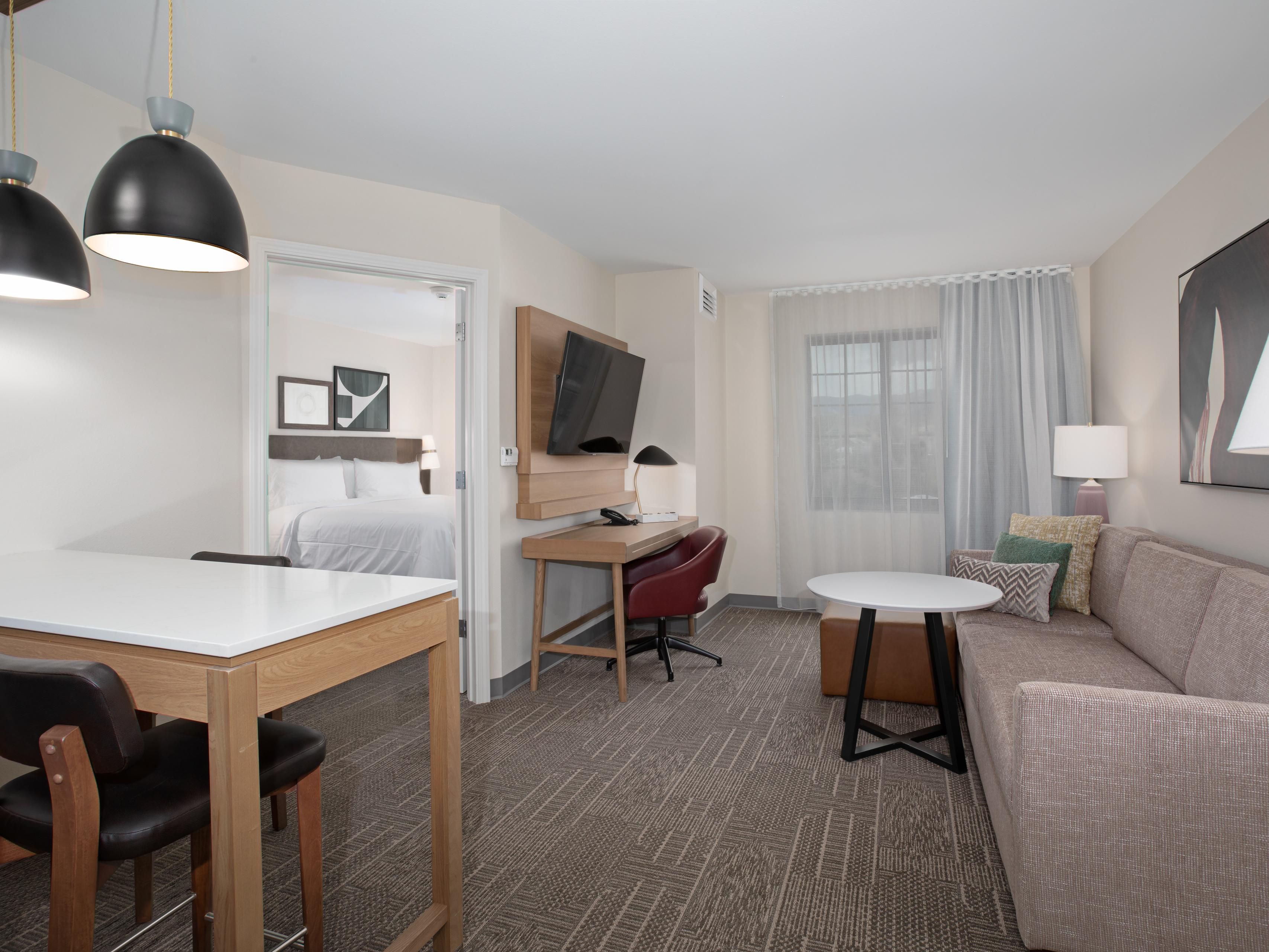 Suite with couch and tables. Bed can be seen in other room