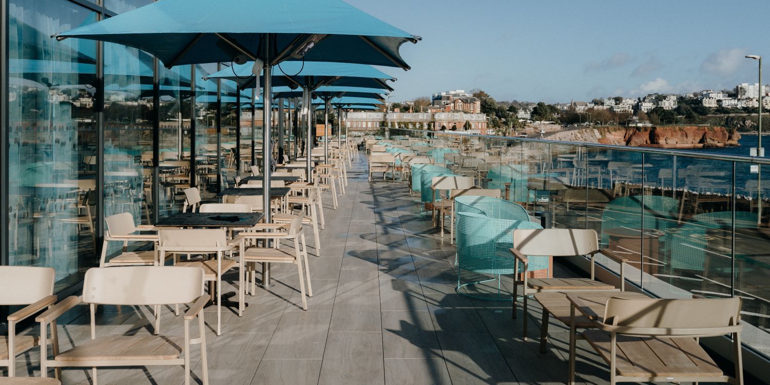 outdoor rooftop dining area with plenty tables and chairs and scenic views of the ocean