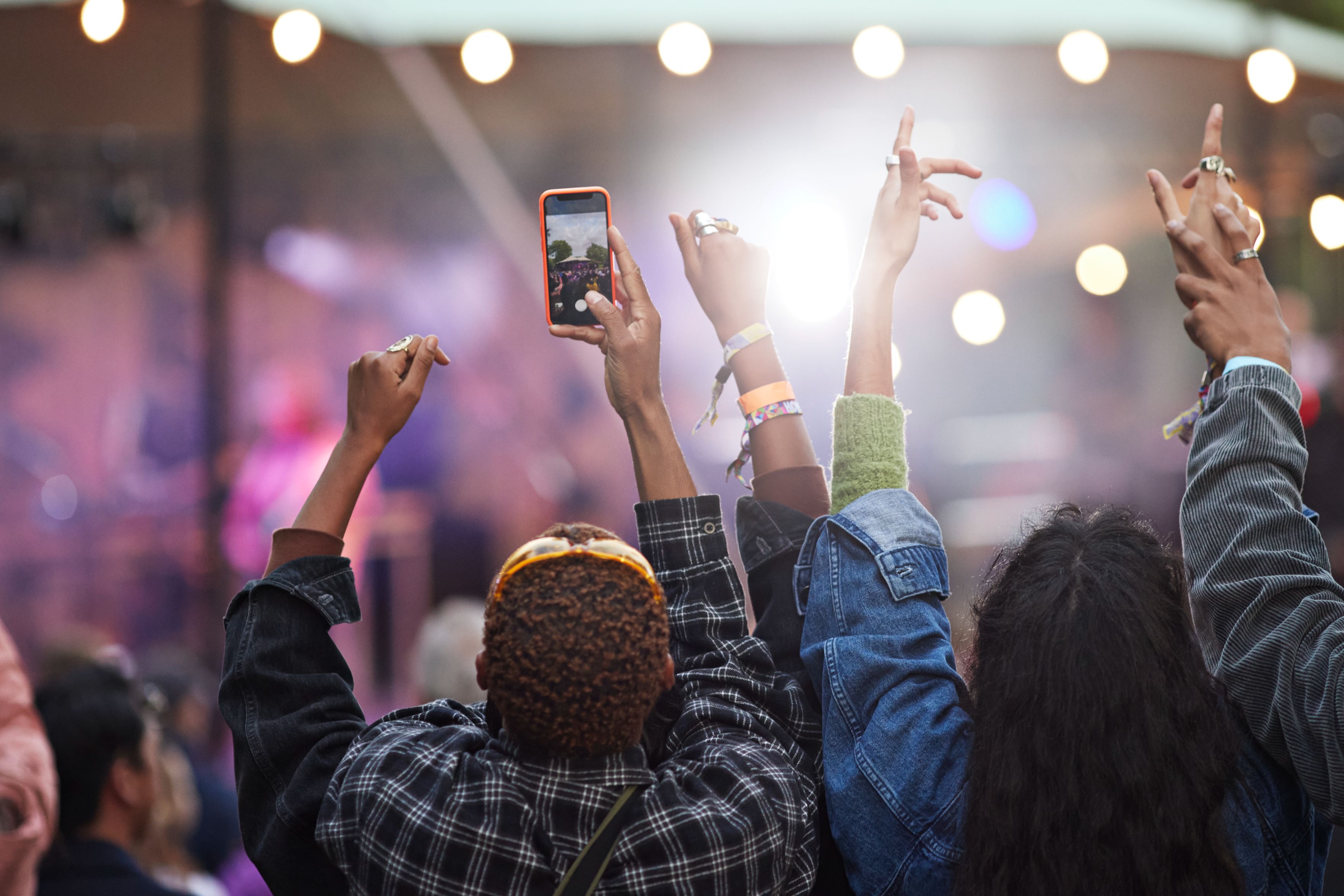 Fans in the crowd at a concert, recording on their phone.