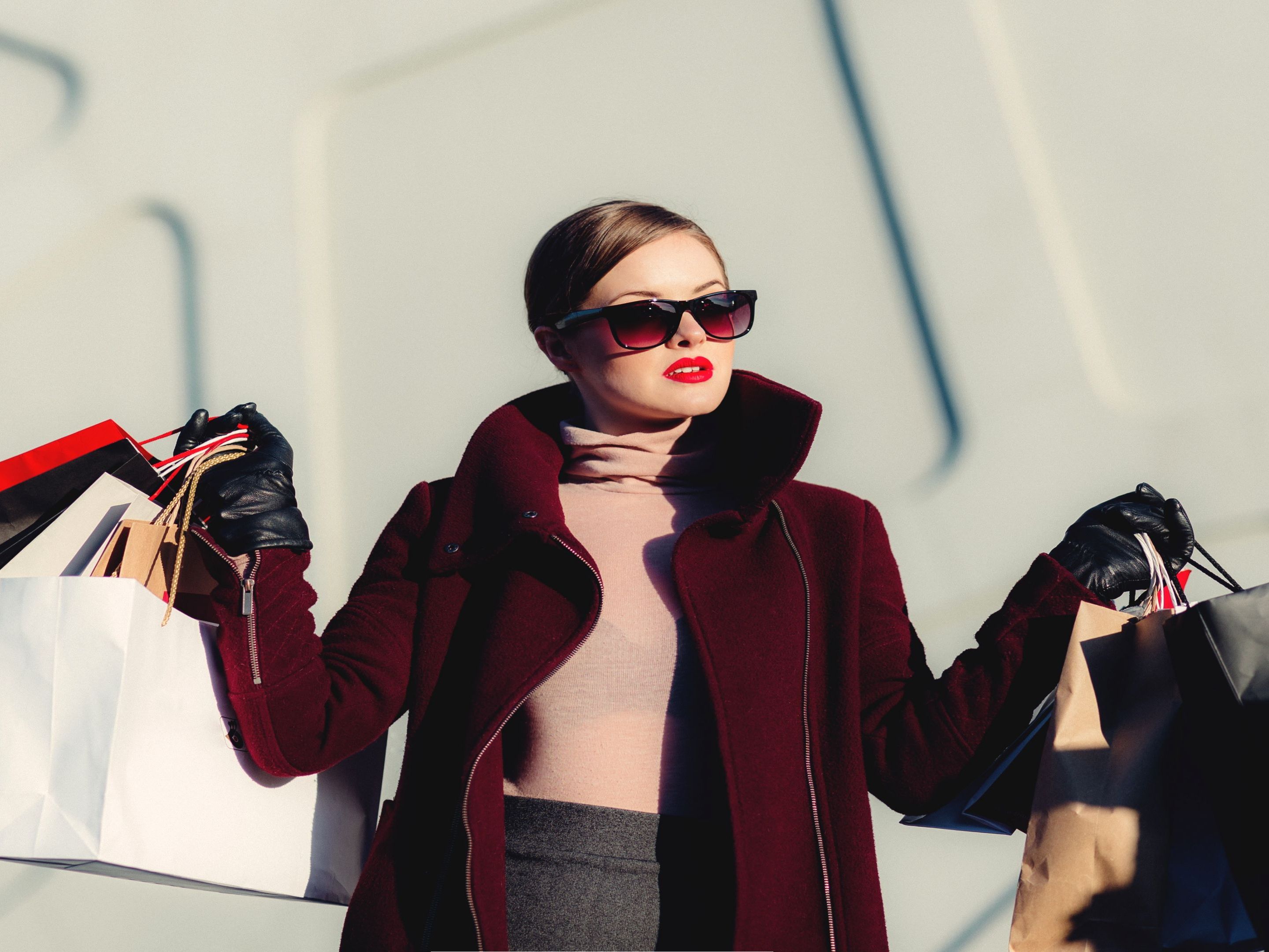 Woman posing in fashionable outfit with shopping bags.