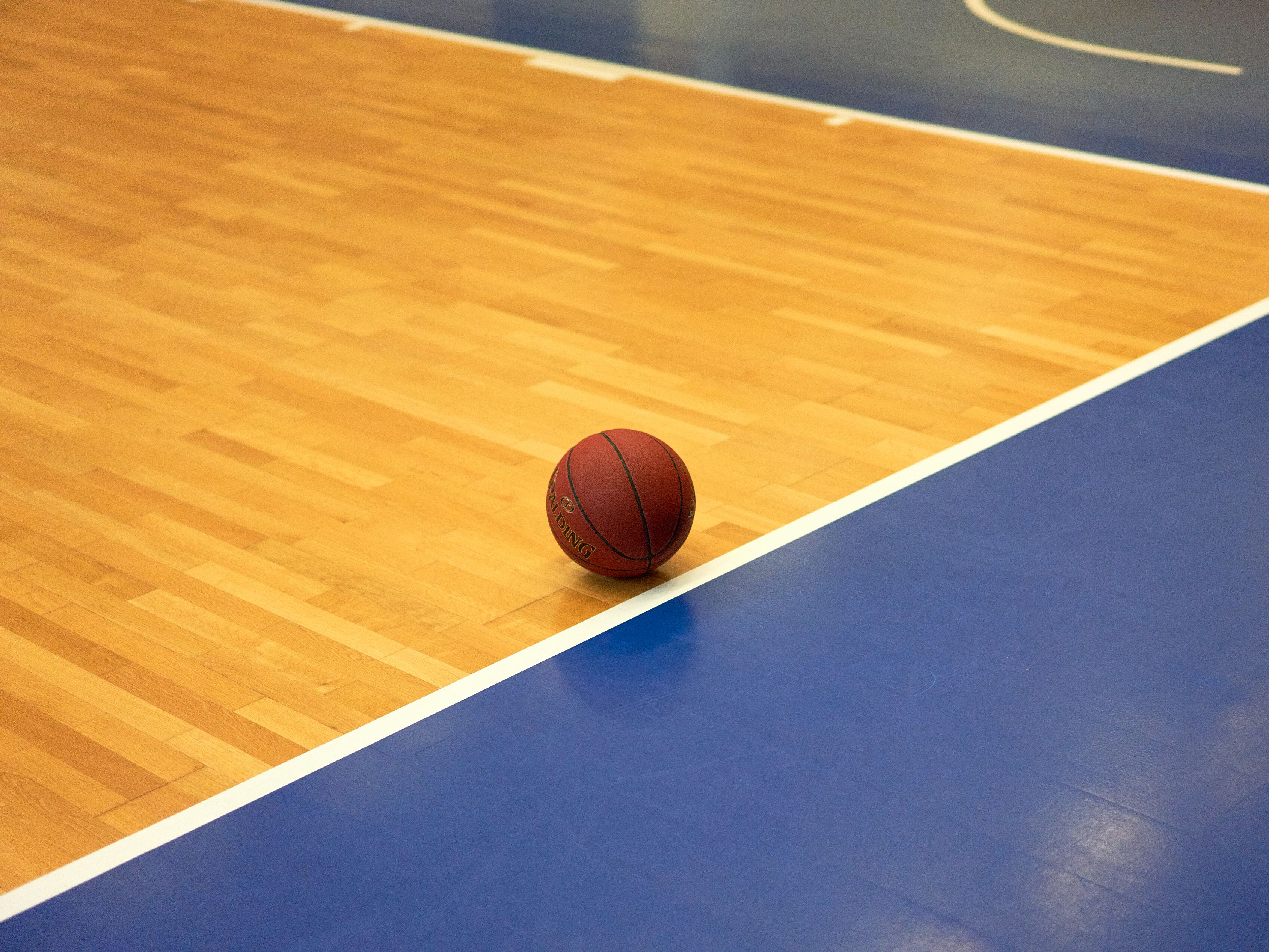 Basketball sitting on a court with blue and tan flooring