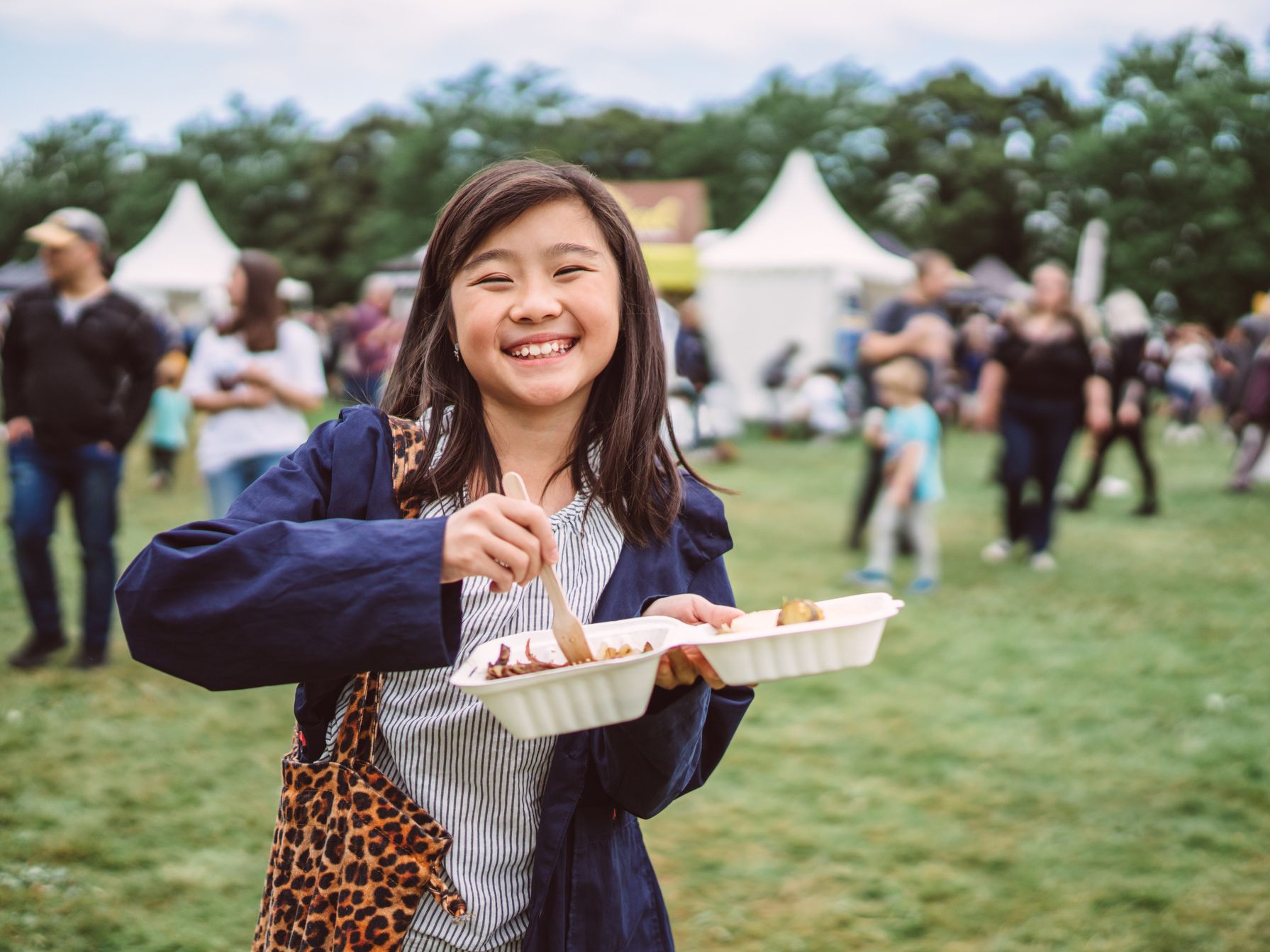 Young girl enjoying some food at a festival.