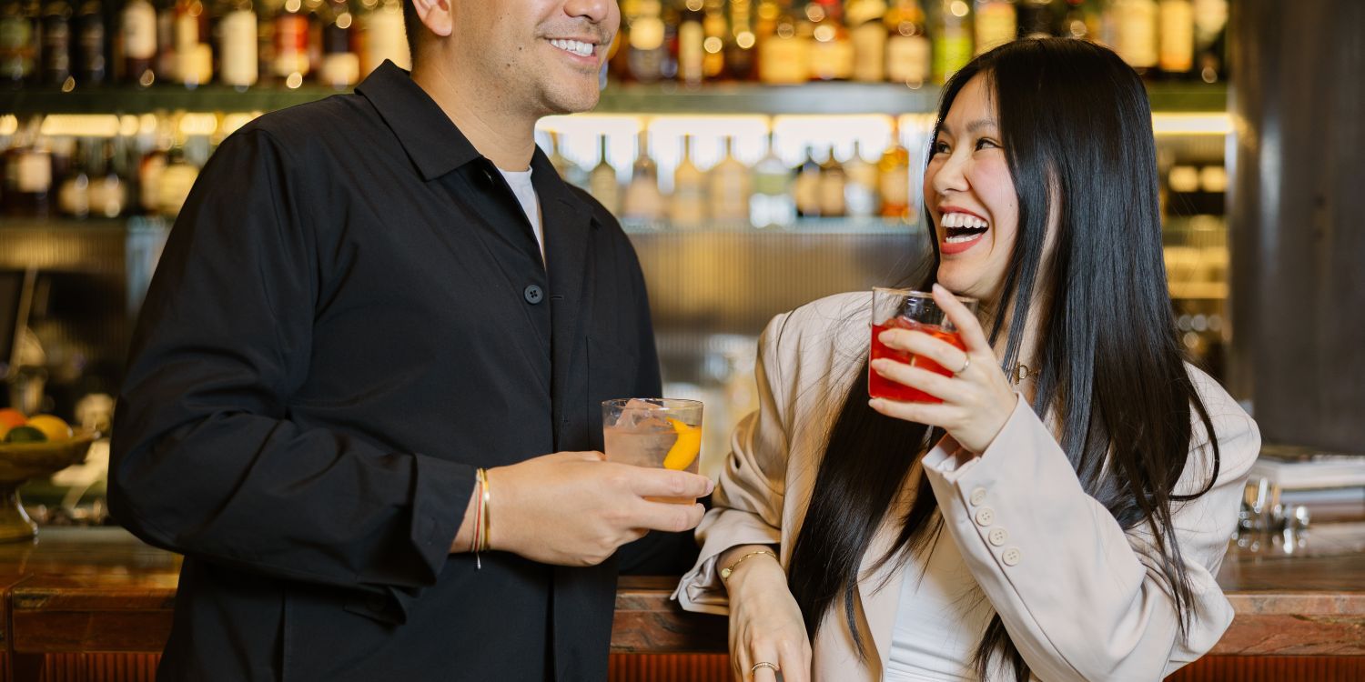 Paar, das vergnügt einen Cocktail an der Bar nippt