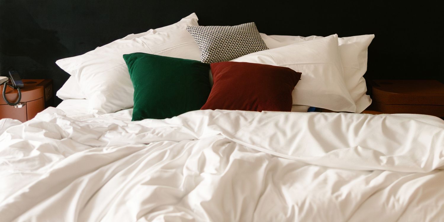 ungemachtes Hotelbett mit vielen Kissen