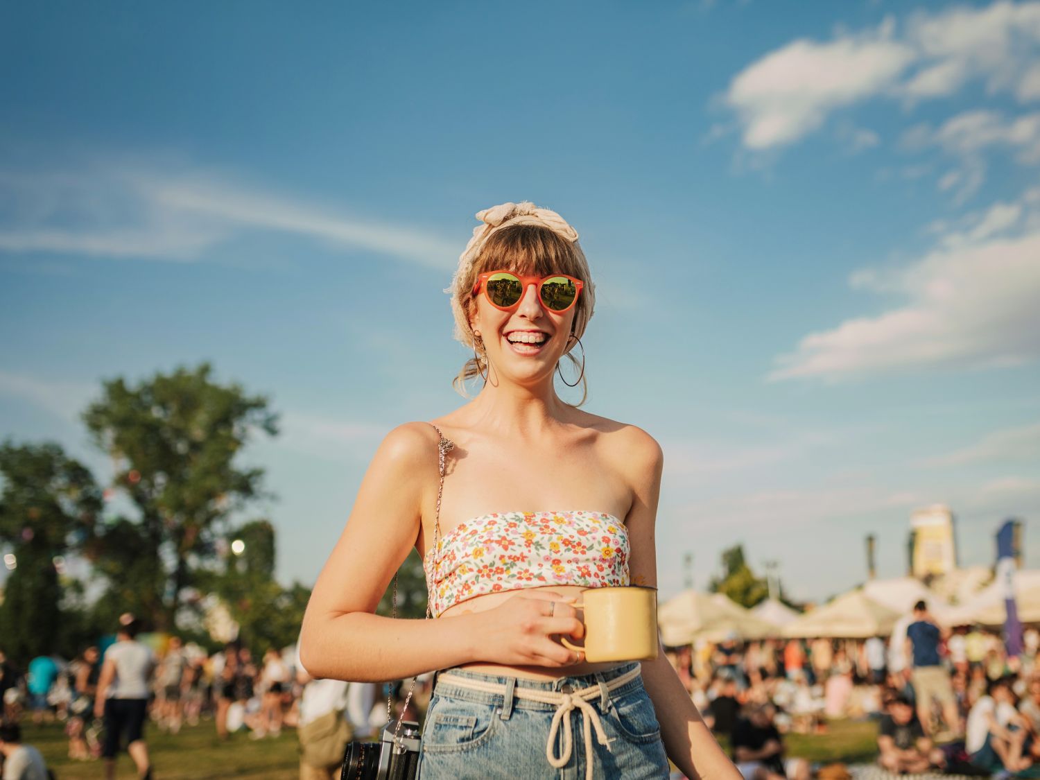 person smiling at a festival holding a mug