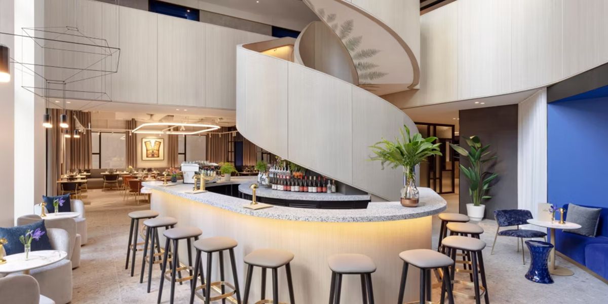 Modern hotel lobby bar with curved counter and seating.