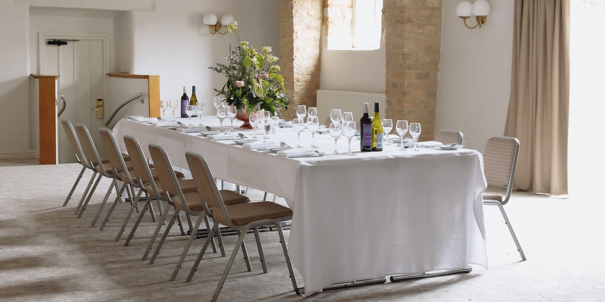 Long banquet table with glasses, wine bottles, plate and utensil settings
