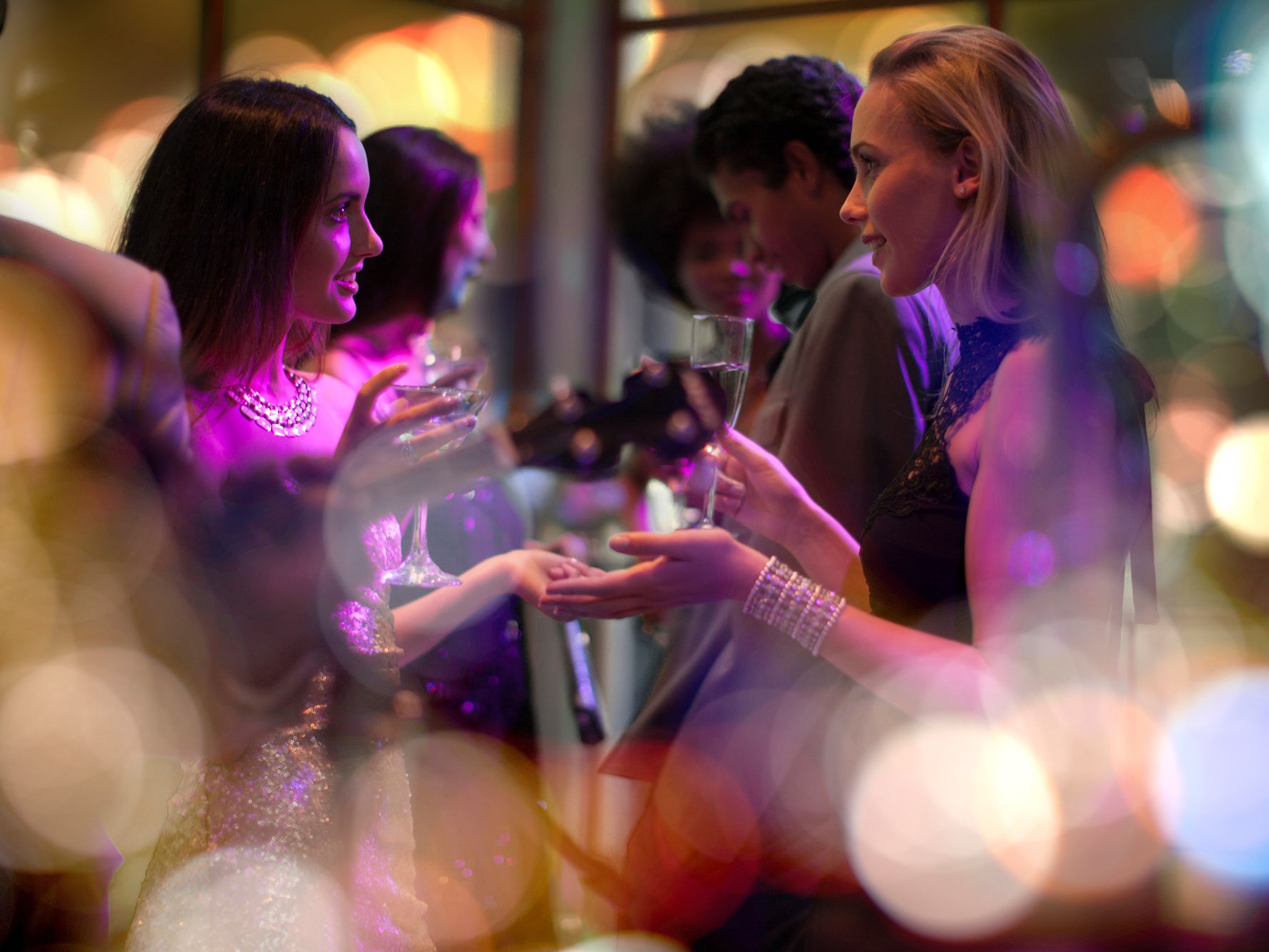 Women having conversation at a party with drinks