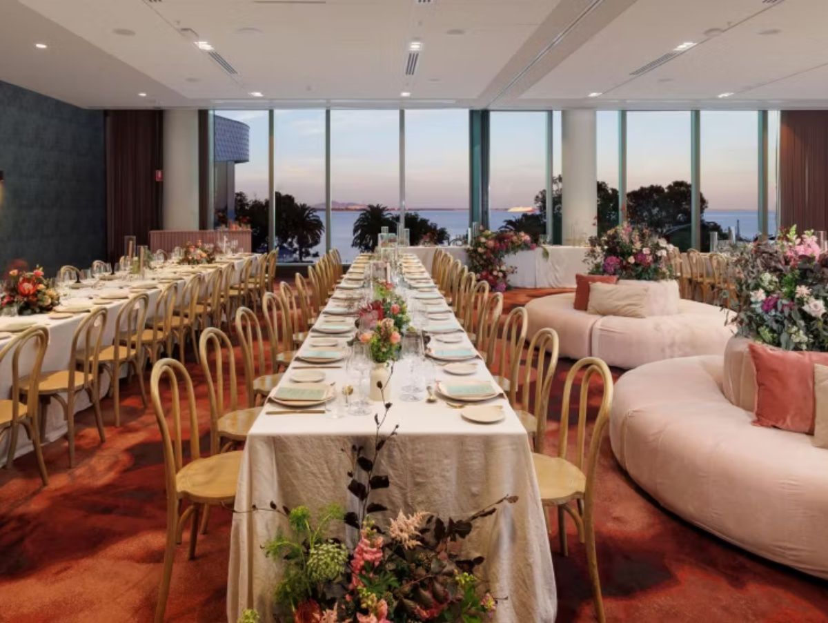 Elegant wedding reception with long tables, floral arrangements, and ocean views.