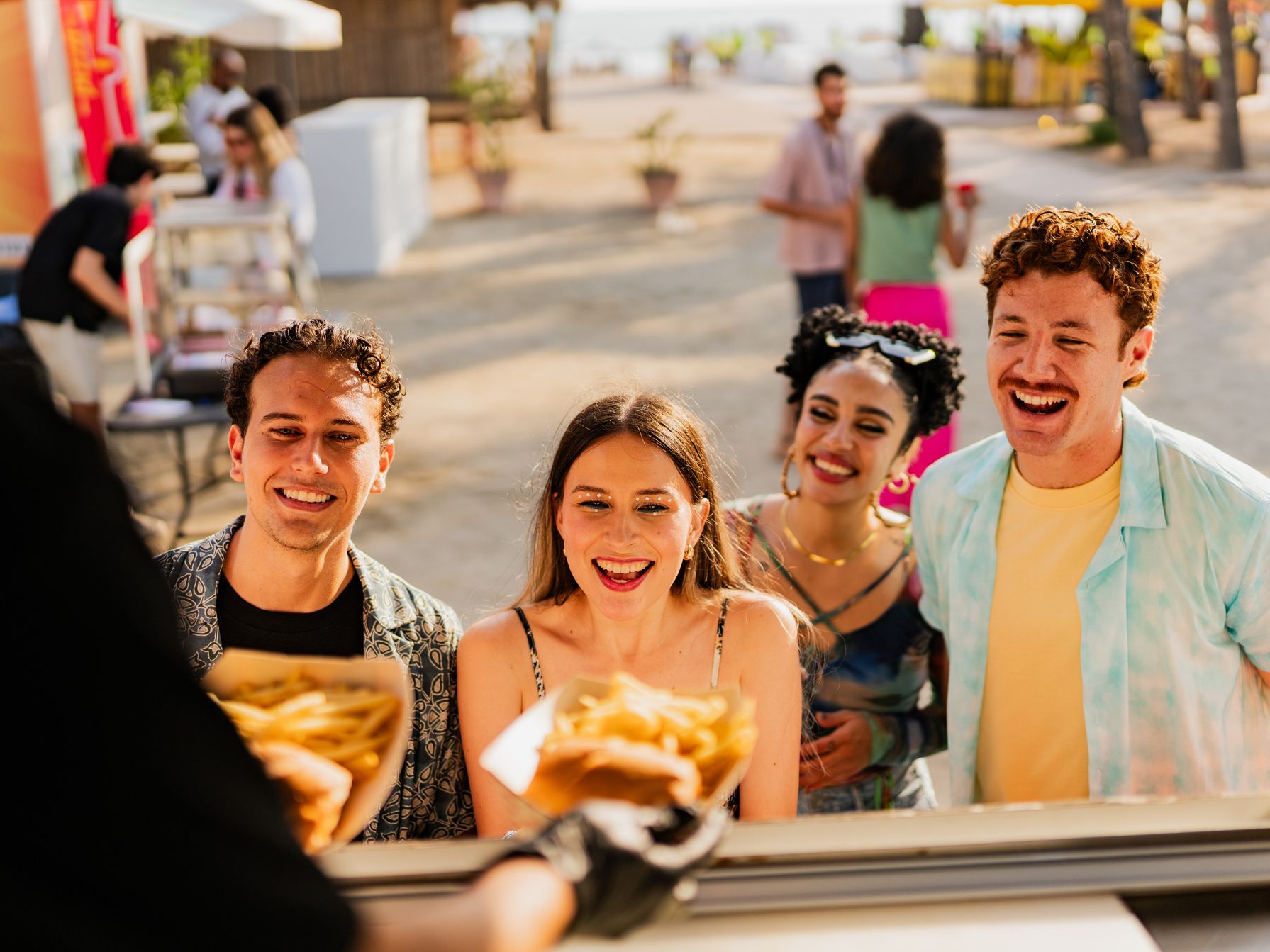 A group getting food from a food truck on beach
