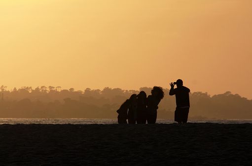 Four adolescent girls pose for a photo taken by their gentleman companion at the Monterey beach in California. I watched these happy young girls dance and laugh and take pictures of each other then quietly take photos of the sunset before posing for a group shot.