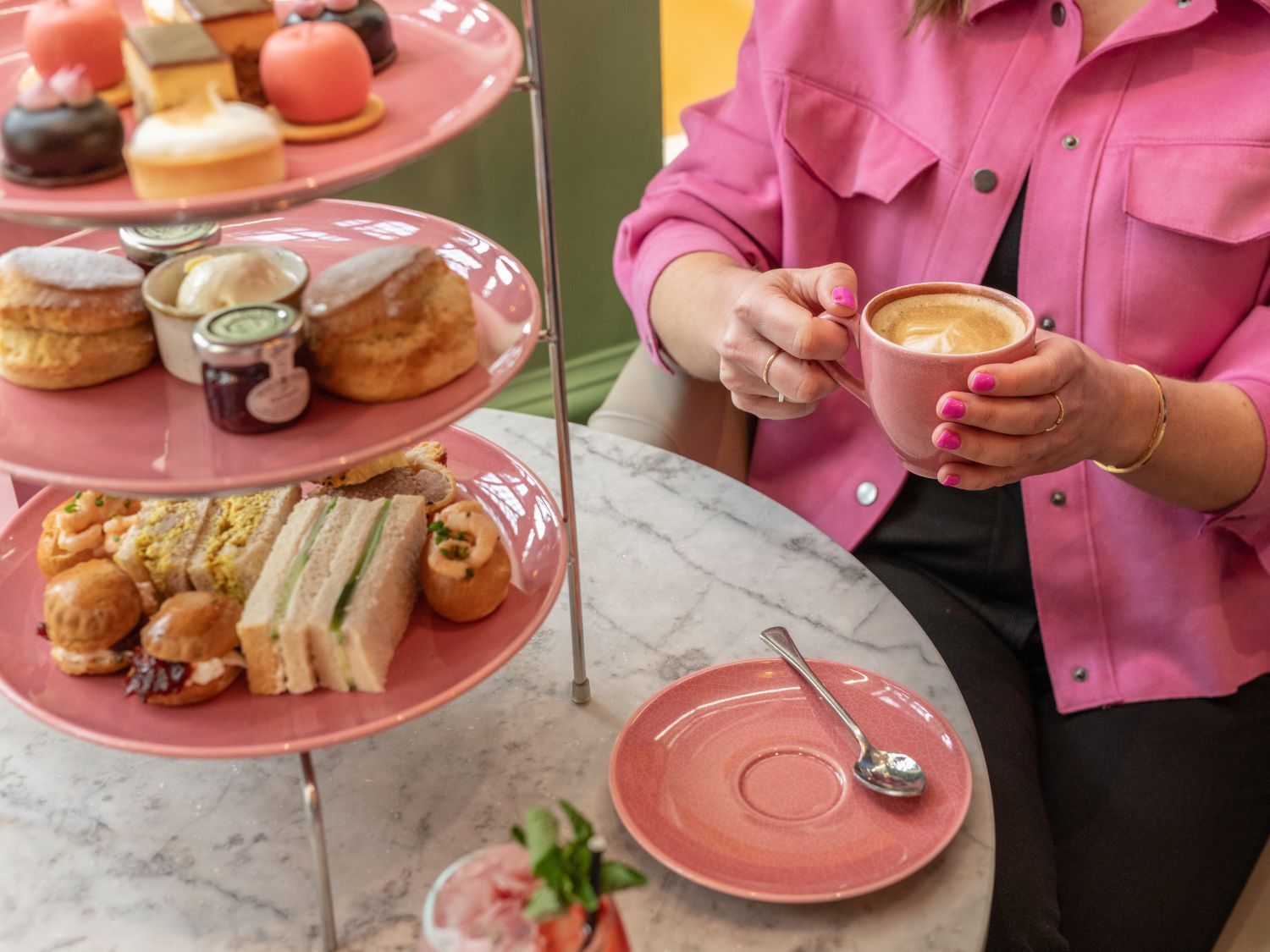 woman in a pink shirt enjoying afternoon tea with three tiered selection