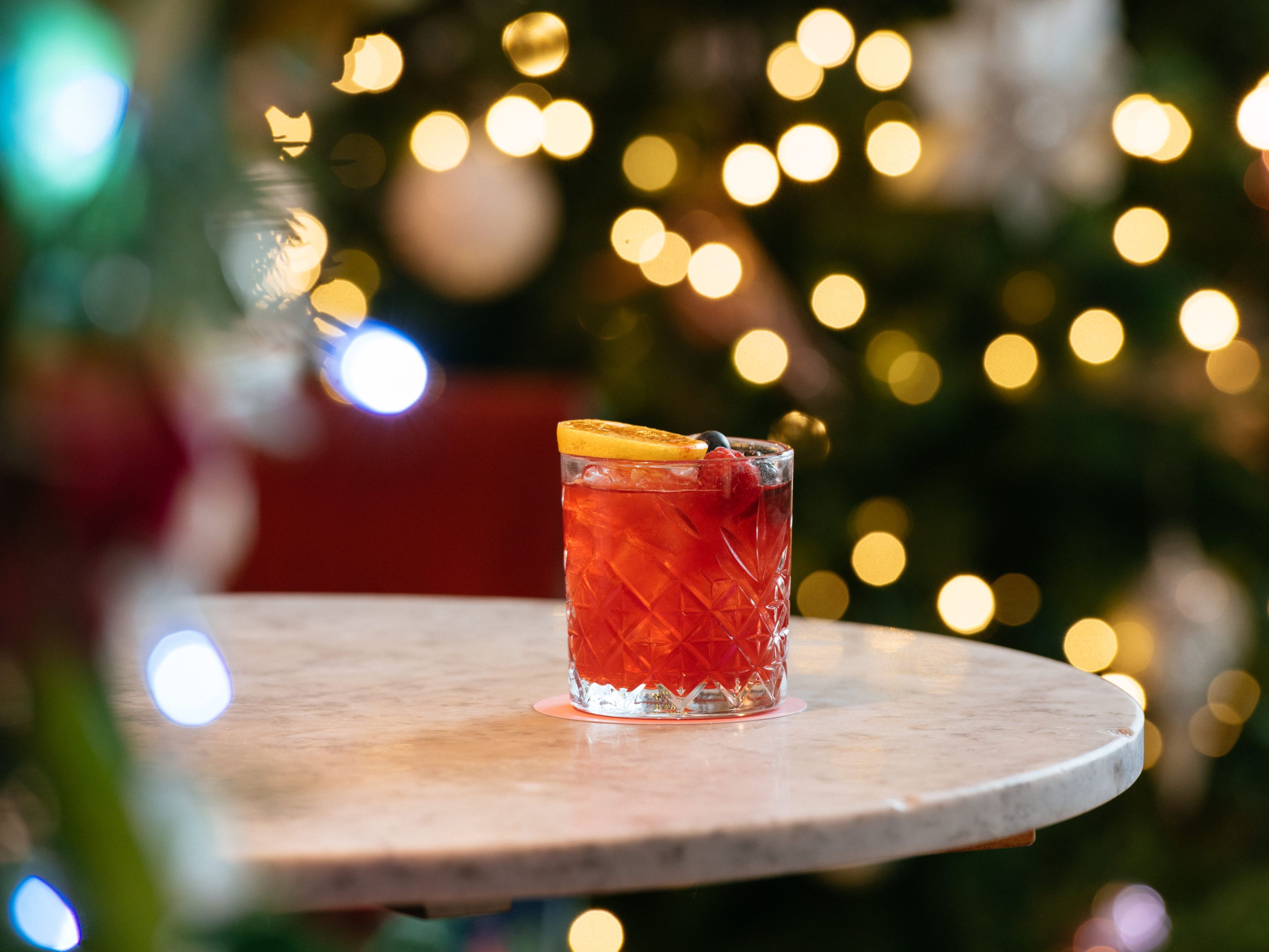 cocktail on a table with Christmas decor in background