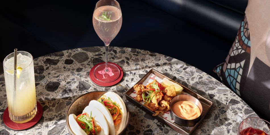 table with cocktails, bao buns, and chicken