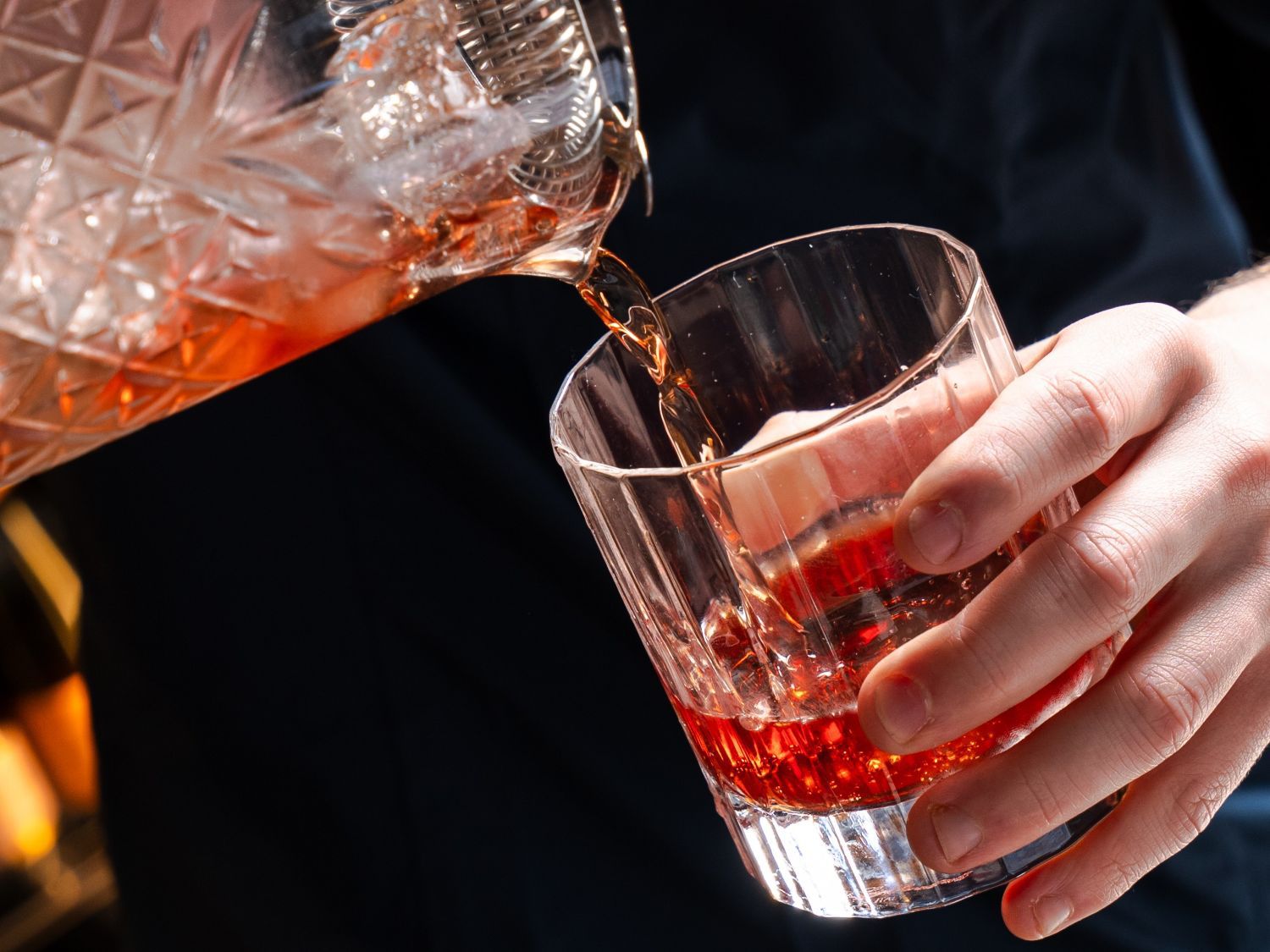 bartender pouring cocktail into glass