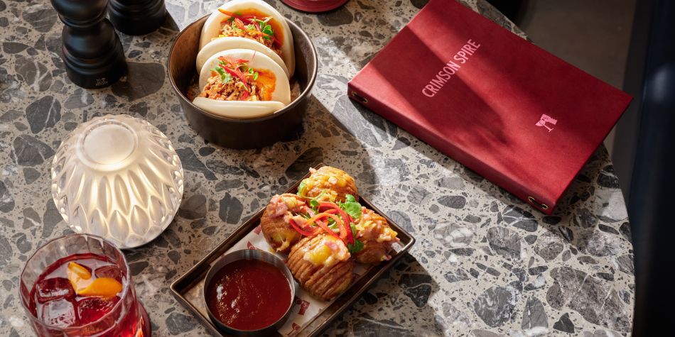 table with bao buns, potato, cocktails and a menu