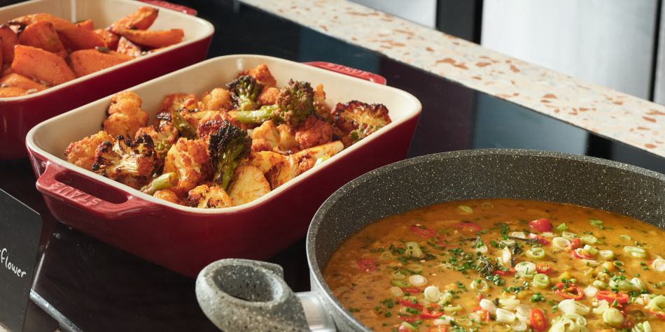 close up on a selection of hot dishes such as harissa cauliflower and sweet potato chips