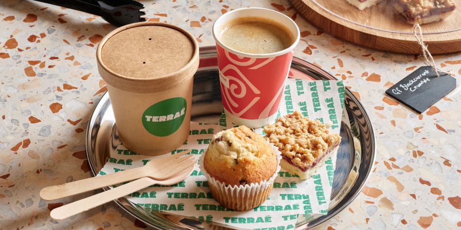 plate of a flapjack slice, a muffin, coffee and a to go box