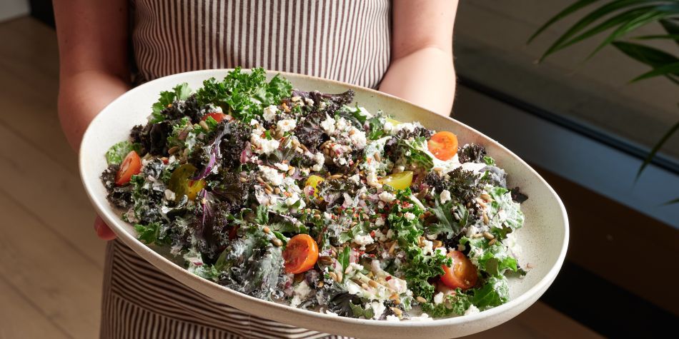 woman in uniform holding a large plate of salad