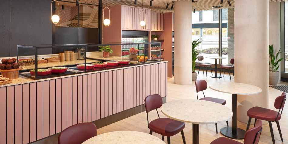 cafe area with pink interior, plenty of seating, and large windows creating a brightly lit room