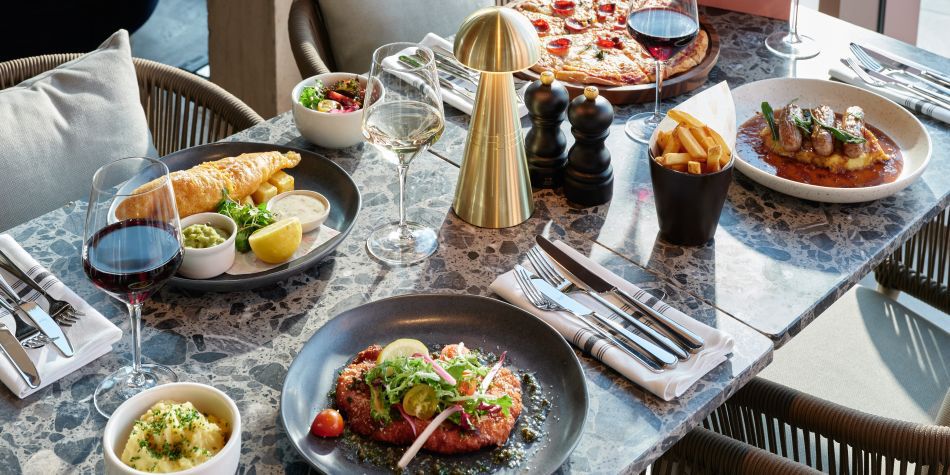 table with four different main plate dishes such as fish and chips