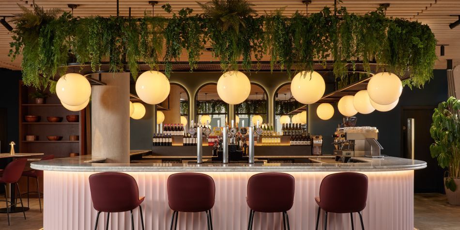 large pink coloured bar with seating and green hanging plants