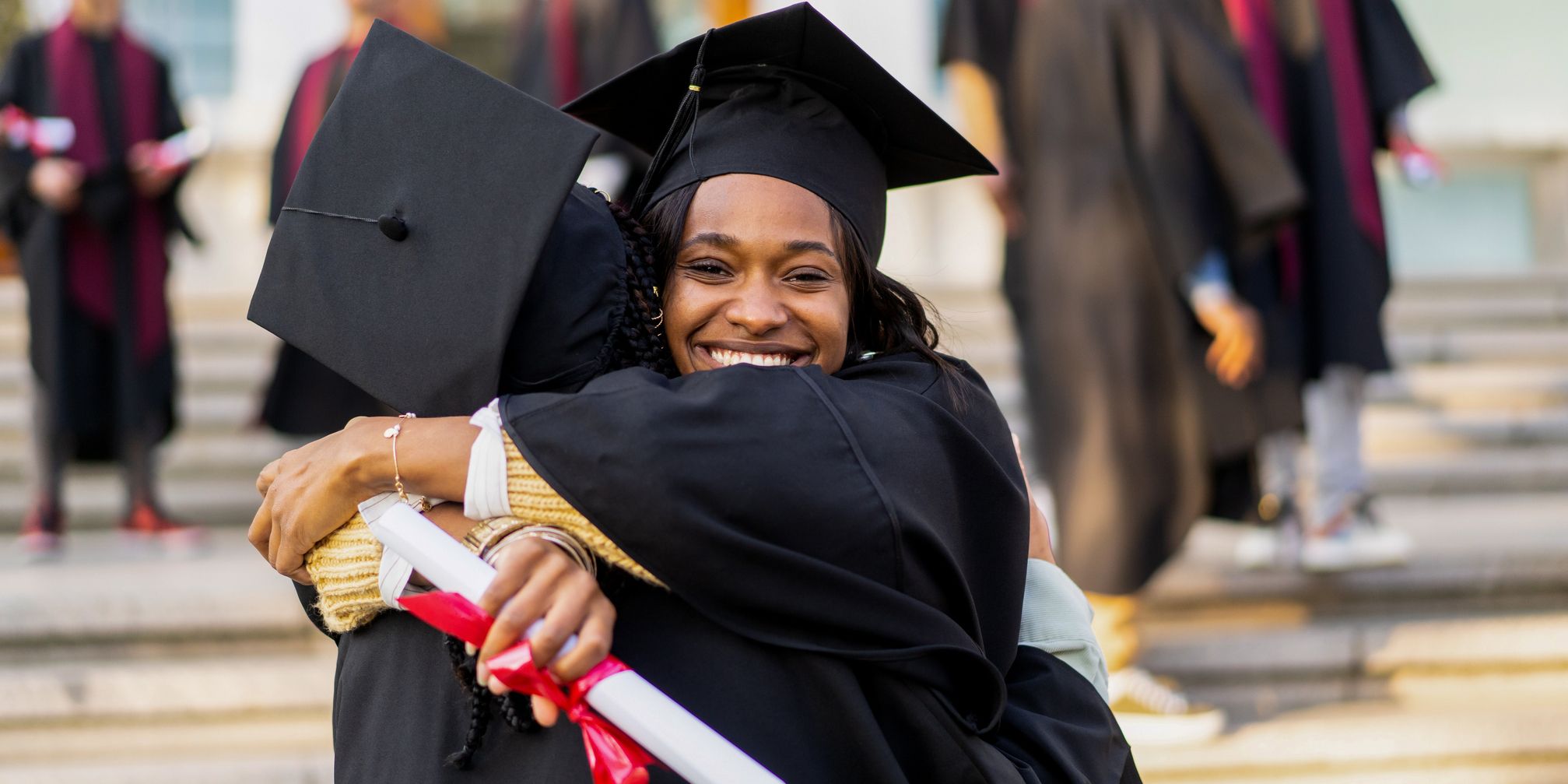 Two graduatates hugging 