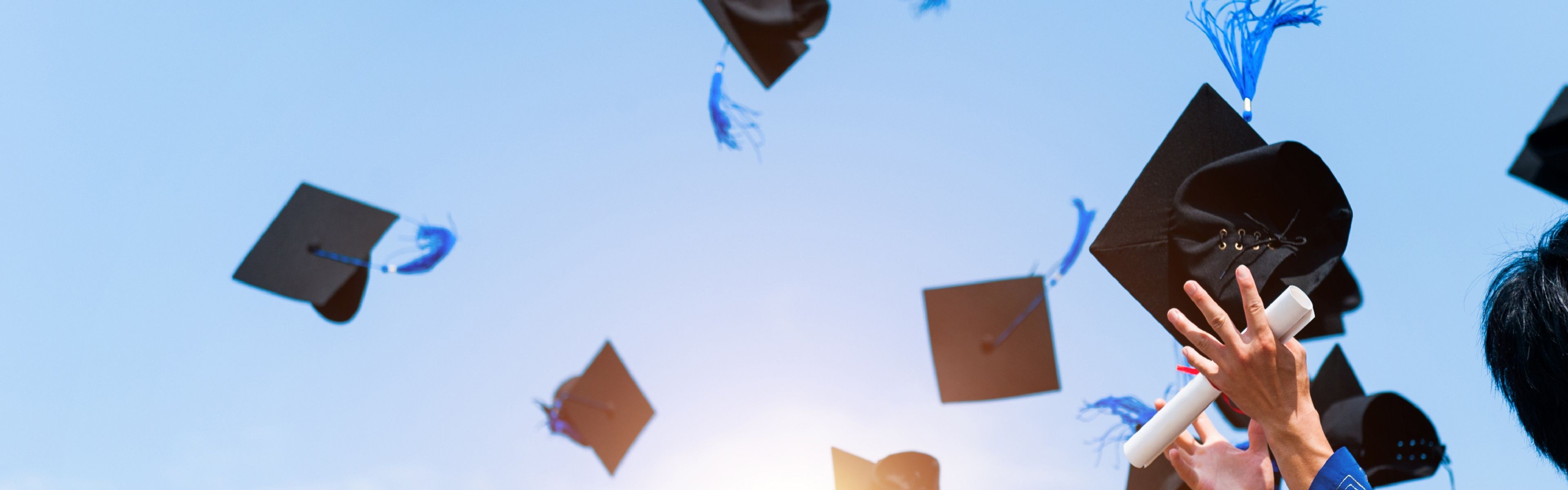 Graduation caps being thrown in the air.