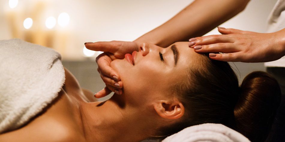 Tratamiento facial con manos masajeando la cara en la habitación del spa