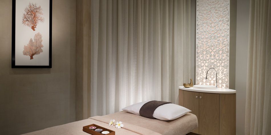 Sala de tratamientos de spa con mesa de masajes y tocador de madera