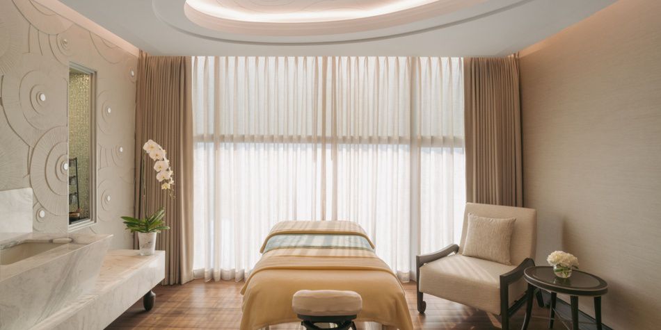 Sala de tratamientos de spa con mesa de masajes y telón de fondo