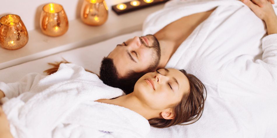 Pareja relajándose en el spa con velas y batas