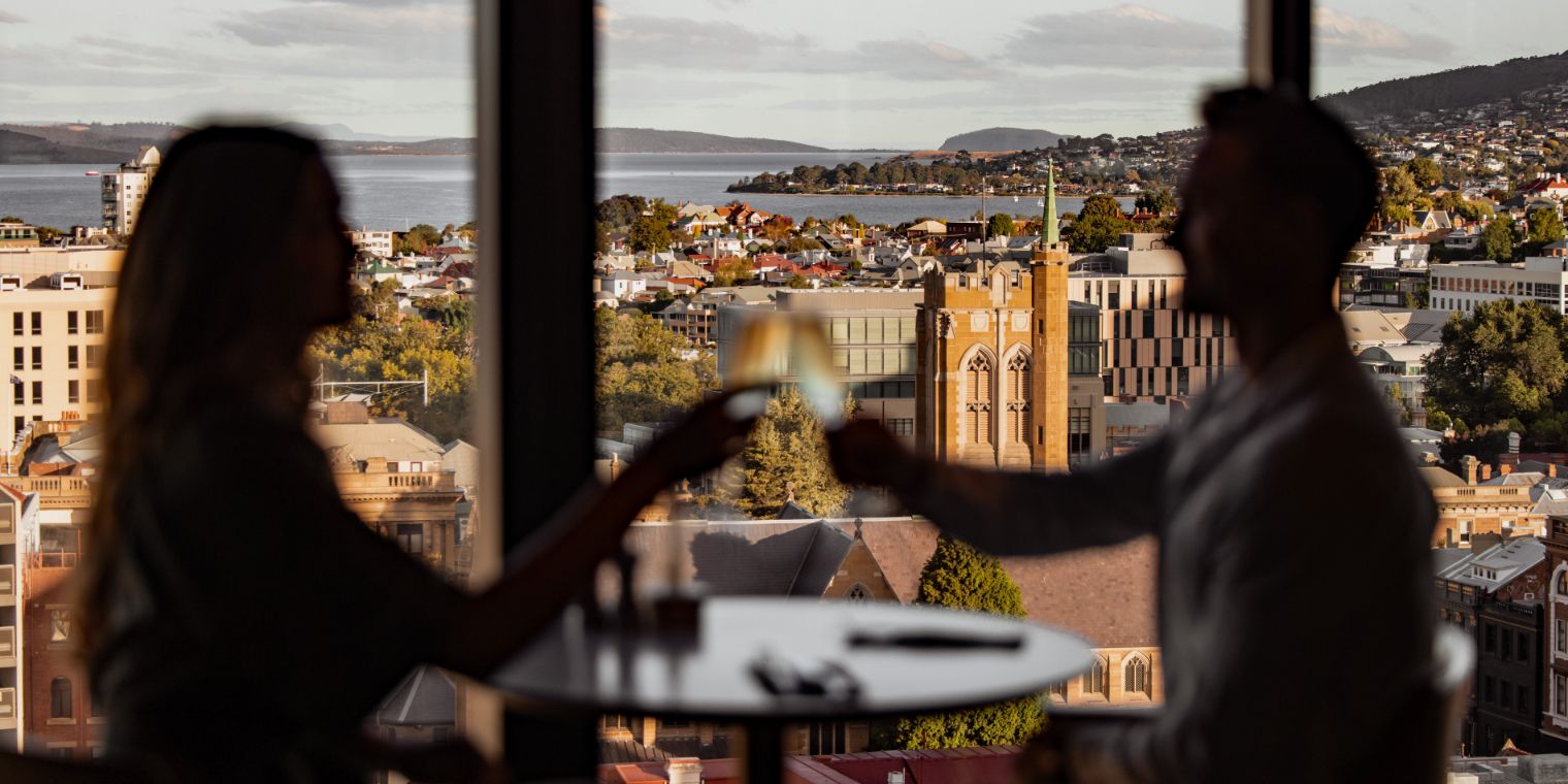 two people toasting with the city in the background