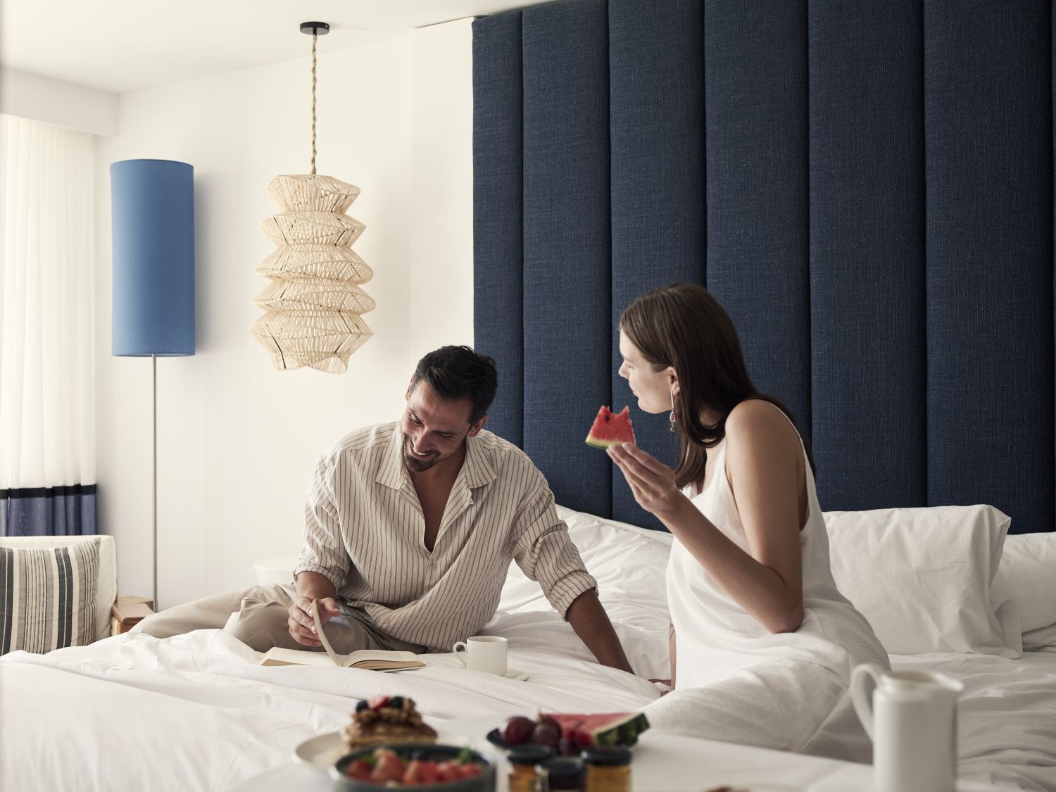 couple enjoying room sevice while sat on bed