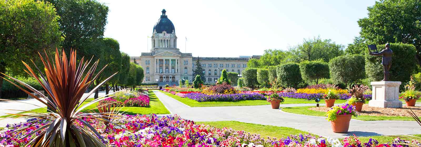 Edifício Associado de Saskatchewan com jardim de flores e árvores em primeiro plano