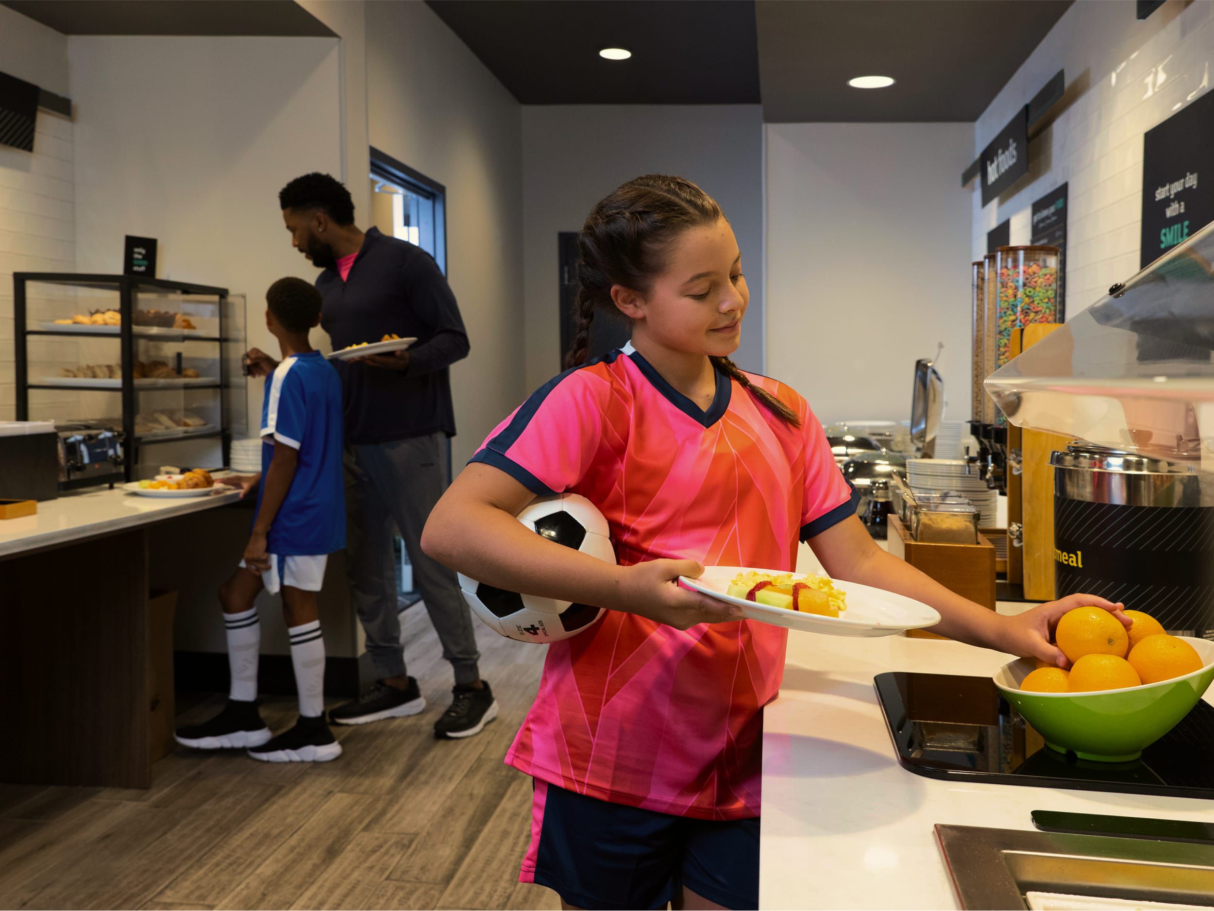 Girl in soccer uniform getting breakfast from buffet