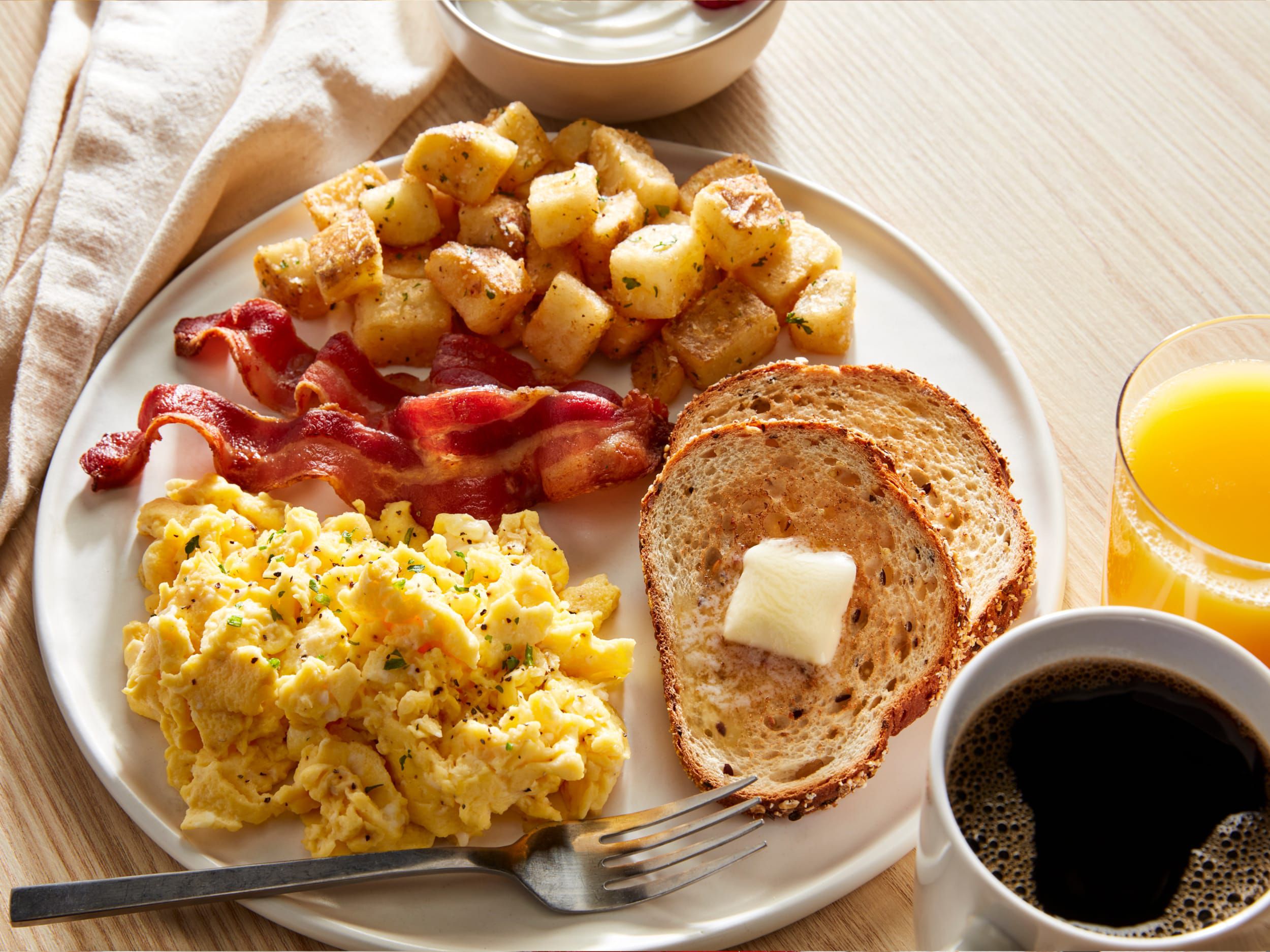 Breakfast food on plate including eggs, bacon, and toast 