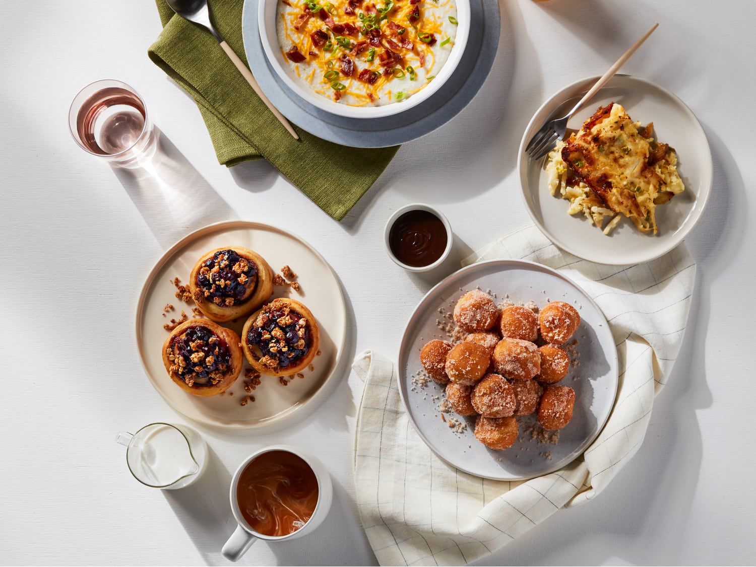 Overhead view of a hotel dining table with coffee, juice, pastries, and plated breakfast dishes.