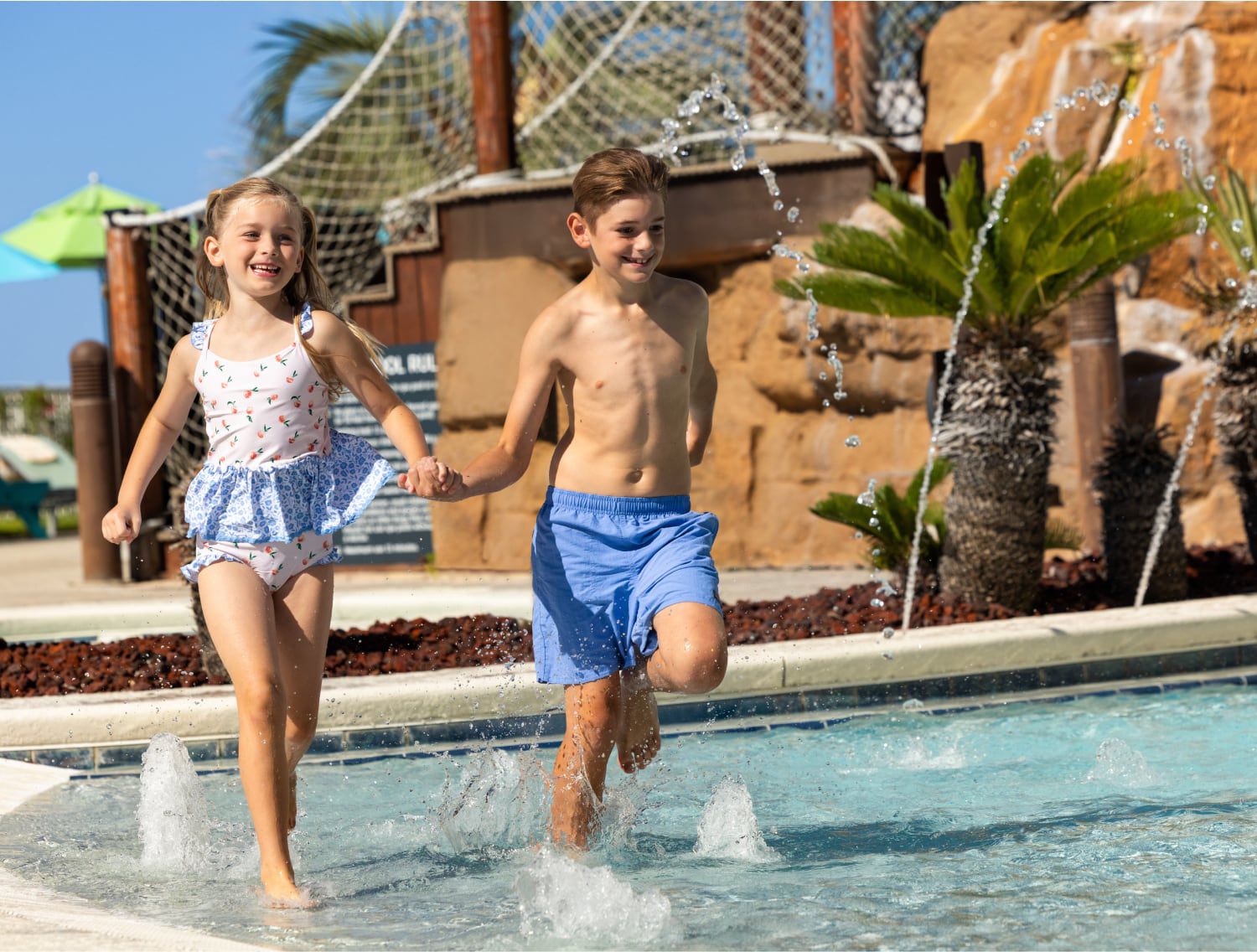 Two children holding hands and playing in a water park