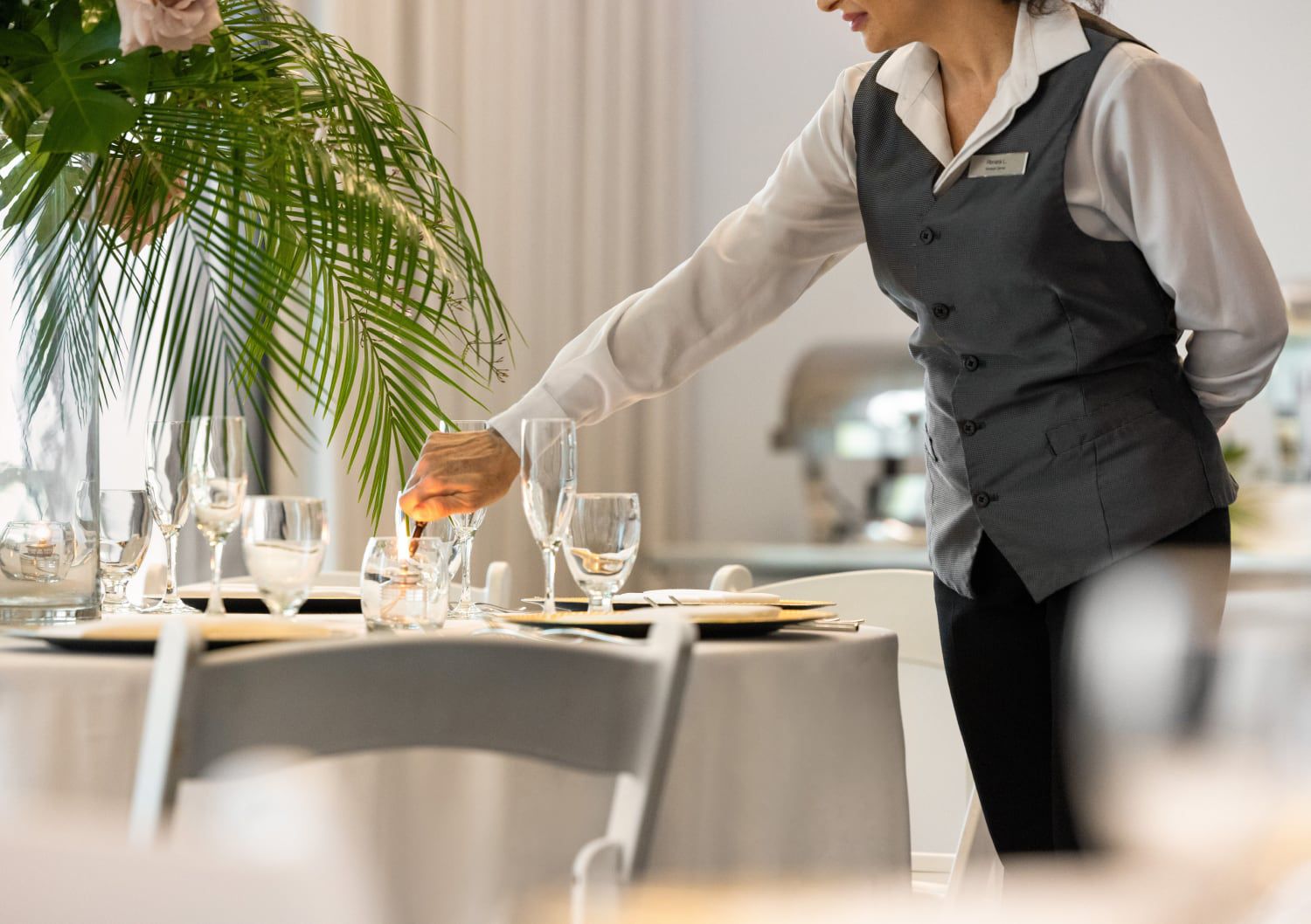 Server lighting a candle on a decorated event table