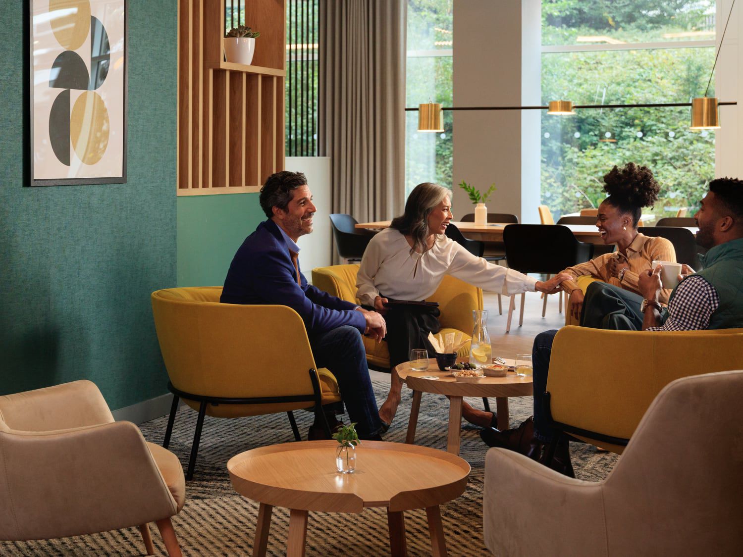Gäste, die sich zu einem zwanglosen Treffen in einer Hotellounge mit modernen gelben Stühlen und runden Tischen zusammengefunden haben.