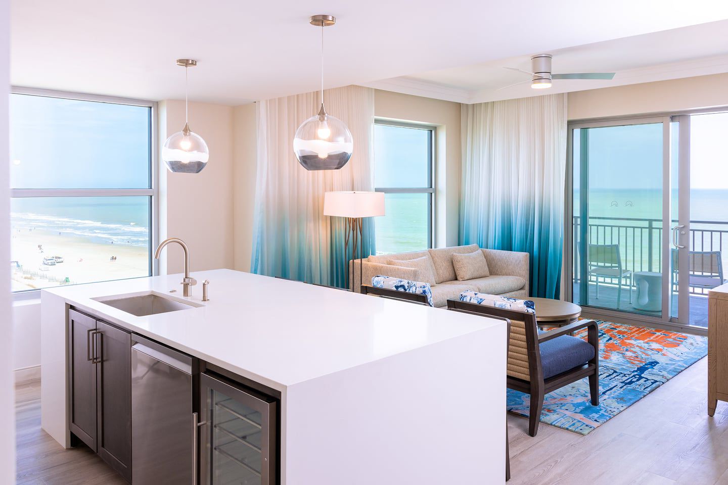 A spacious suite with kitchen, living area, and balcony overlooking the ocean.