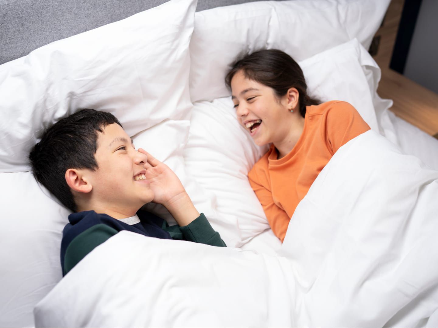 Des enfants rient sur un lit