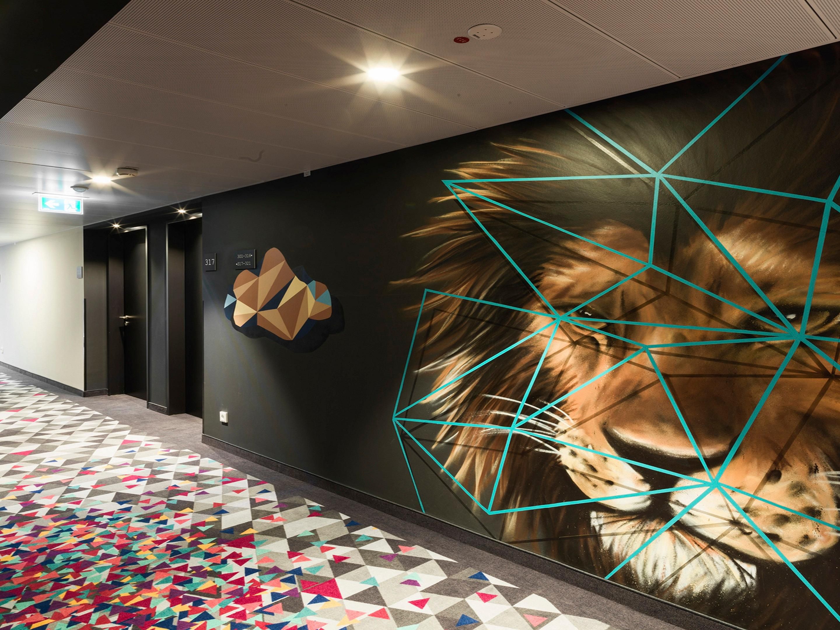 Discover our unique design concept, where Ruhrpott heritage meets contemporary urban flair. Our interiors tell the story of Essen’s industrial past with a creative twist, featuring striking artwork by Björn Holzweg. His geometric wildlife portraits add a modern edge, inviting you to embark on a visual journey through history and nature.